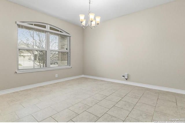 empty room featuring a chandelier and baseboards