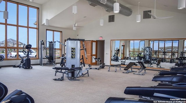 workout area with carpet flooring, visible vents, a towering ceiling, and ceiling fan