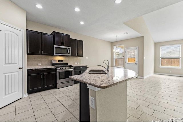 kitchen featuring light tile patterned floors, backsplash, stainless steel appliances, and a sink