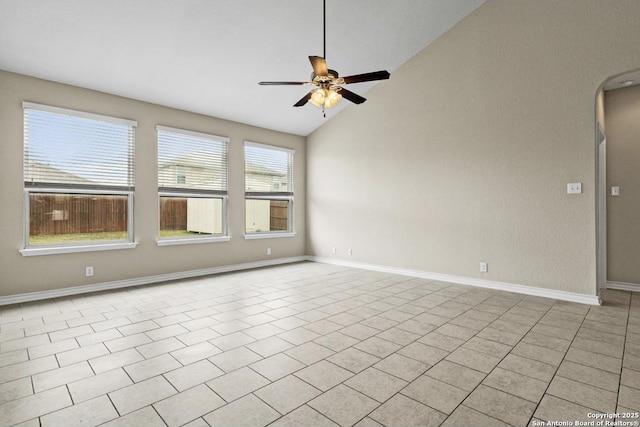 spare room with baseboards, ceiling fan, vaulted ceiling, light tile patterned floors, and arched walkways