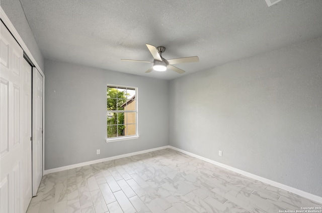 unfurnished bedroom with baseboards, a closet, marble finish floor, a textured ceiling, and a ceiling fan