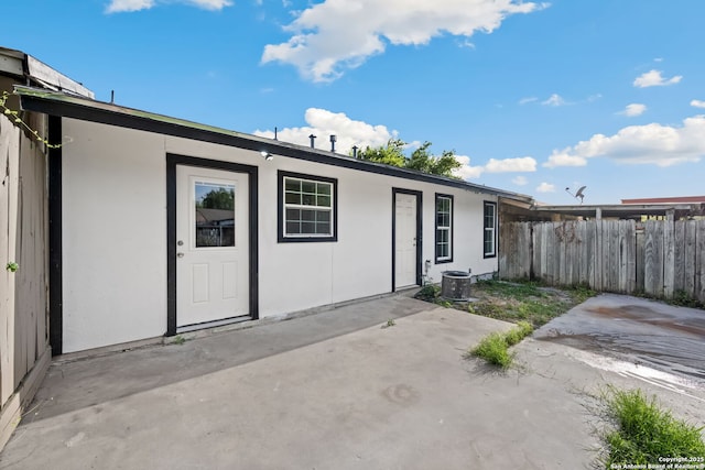 rear view of house featuring a patio, fence, and stucco siding