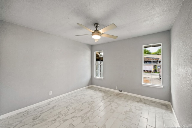 unfurnished room with a ceiling fan, baseboards, marble finish floor, and a textured ceiling