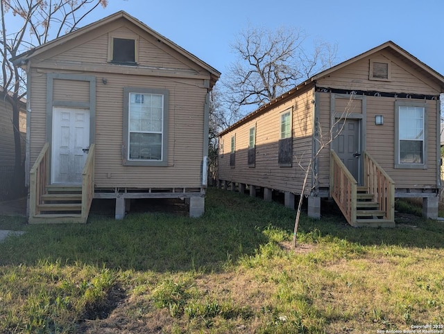 view of front facade featuring entry steps, a front yard, and cooling unit