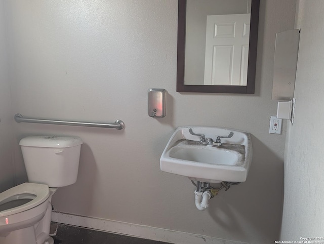 bathroom featuring toilet, baseboards, and a sink