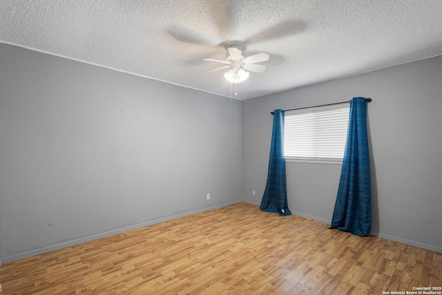 spare room with wood finished floors, a ceiling fan, baseboards, and a textured ceiling