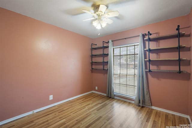 empty room with wood finished floors, baseboards, and ceiling fan