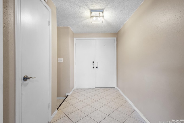 entrance foyer featuring light tile patterned flooring, a textured ceiling, and baseboards