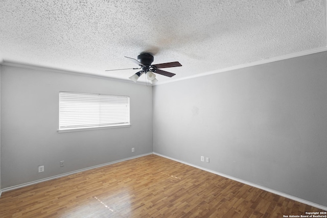 spare room featuring wood finished floors, a ceiling fan, baseboards, ornamental molding, and a textured ceiling