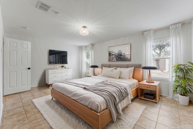 bedroom with multiple windows, light tile patterned flooring, and visible vents