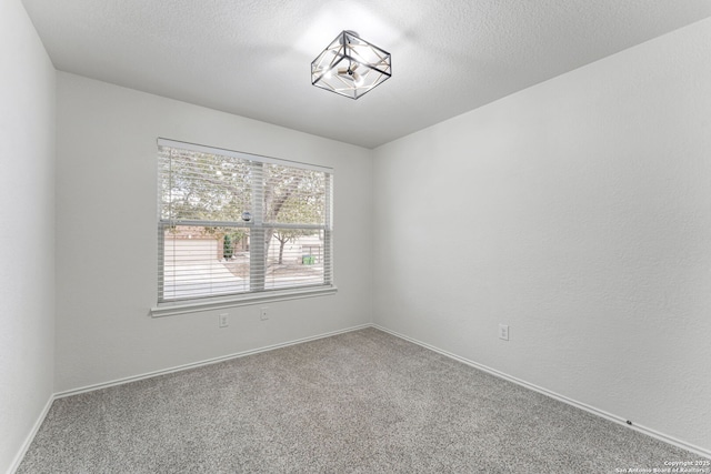 carpeted spare room featuring a textured ceiling and baseboards