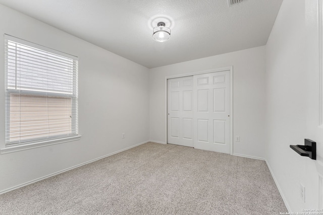 unfurnished bedroom with carpet flooring, baseboards, a closet, and a textured ceiling