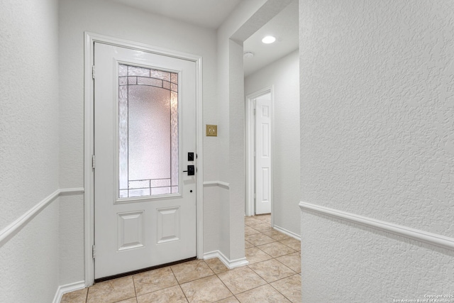 entryway with light tile patterned floors, baseboards, and a textured wall