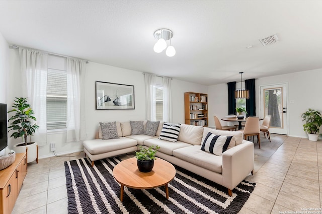 living area featuring light tile patterned floors, visible vents, and baseboards