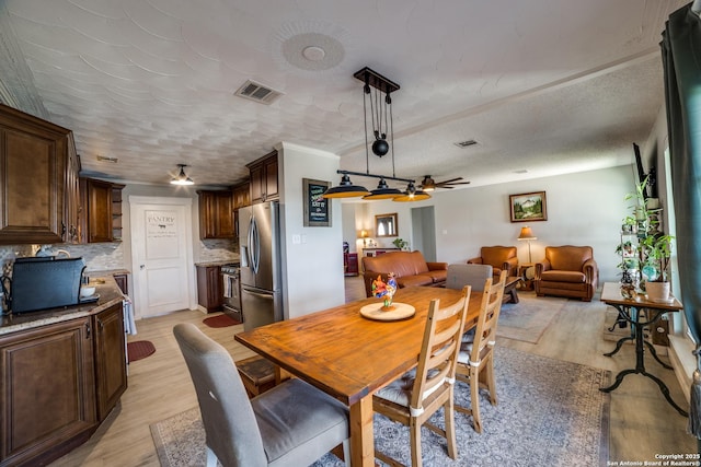 dining space featuring light wood-style flooring, a ceiling fan, and visible vents