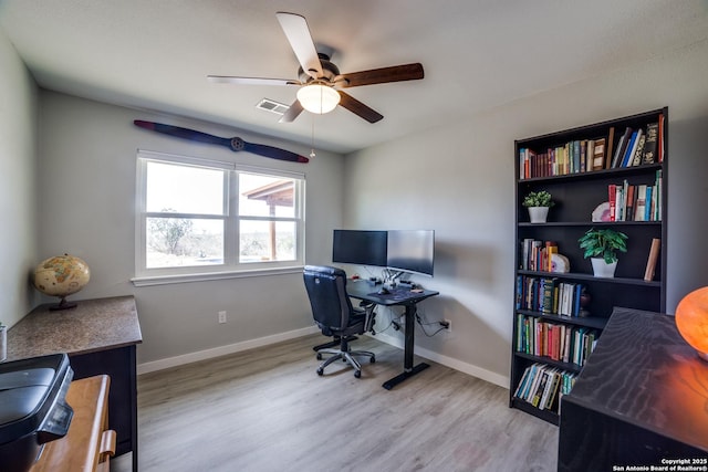 home office featuring a ceiling fan, wood finished floors, visible vents, and baseboards