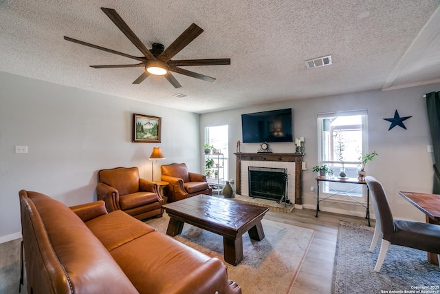 living area with visible vents, light wood-style floors, a healthy amount of sunlight, and a ceiling fan