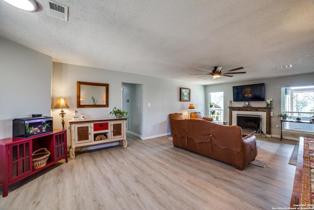 living room featuring visible vents, plenty of natural light, wood finished floors, and a ceiling fan