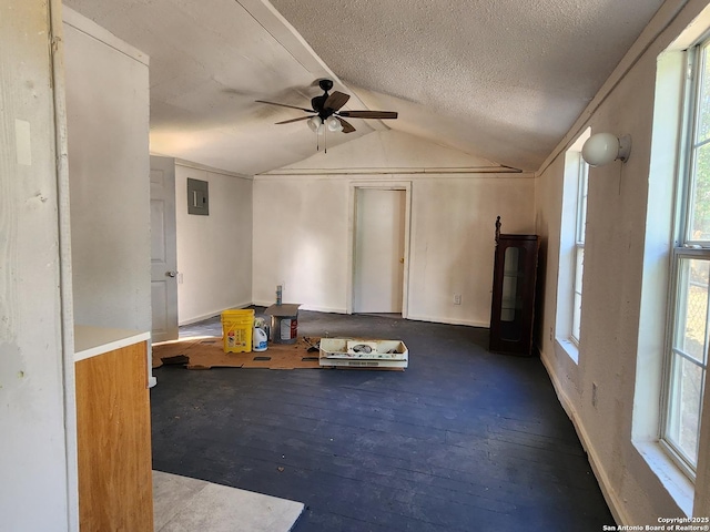 interior space with electric panel, a textured ceiling, hardwood / wood-style floors, ceiling fan, and vaulted ceiling