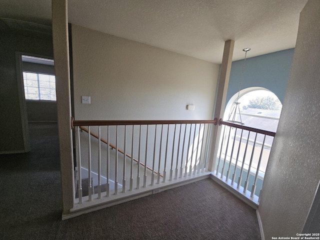 hallway featuring carpet flooring and a textured ceiling