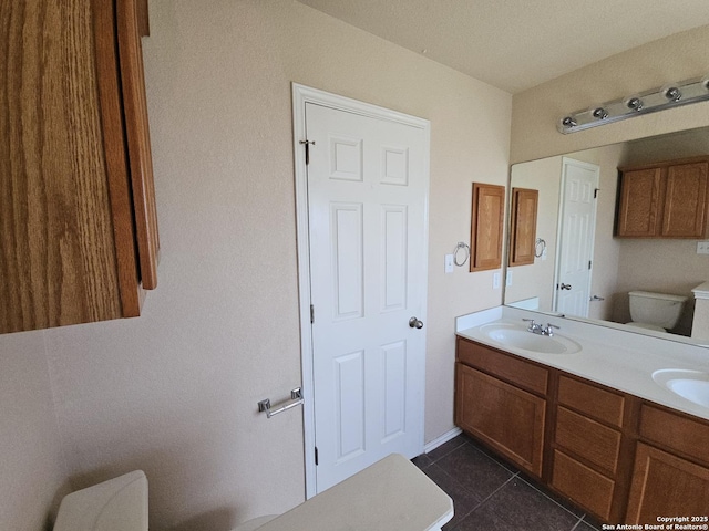 bathroom with a sink, toilet, double vanity, and tile patterned floors