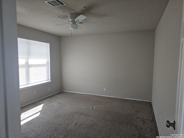 spare room featuring visible vents, a textured ceiling, carpet flooring, baseboards, and ceiling fan