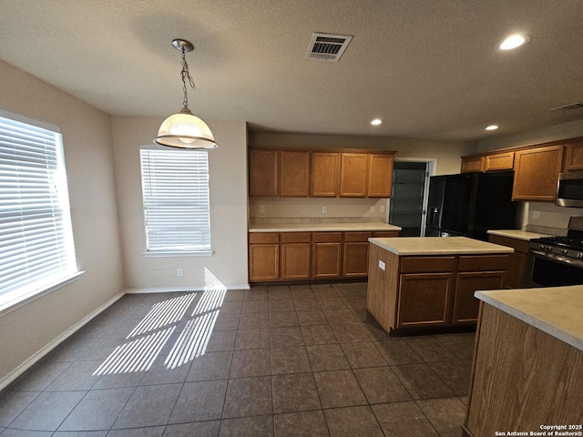 kitchen with a healthy amount of sunlight, visible vents, a kitchen island, light countertops, and appliances with stainless steel finishes