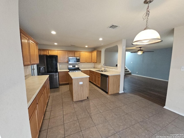 kitchen with visible vents, a kitchen island, light countertops, stainless steel appliances, and a sink