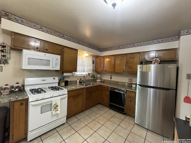 kitchen featuring a sink, white appliances, brown cabinets, and light tile patterned flooring