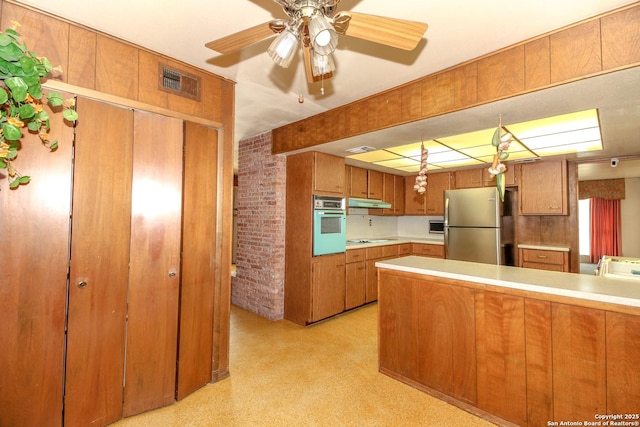 kitchen with visible vents, light countertops, brown cabinets, a peninsula, and white appliances