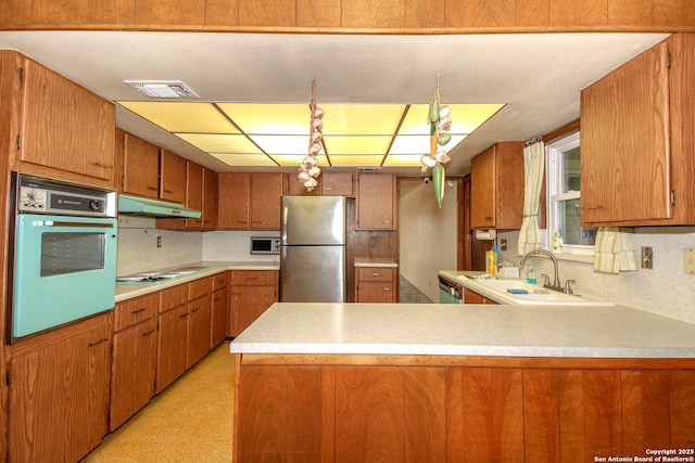 kitchen with visible vents, under cabinet range hood, a sink, stainless steel appliances, and brown cabinetry