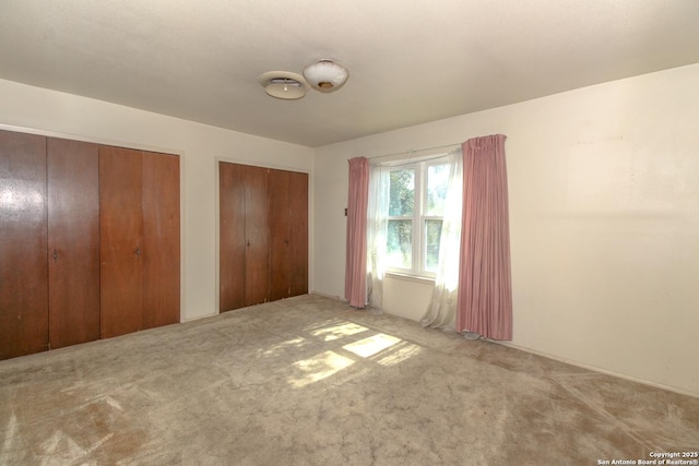 unfurnished bedroom featuring carpet and multiple closets