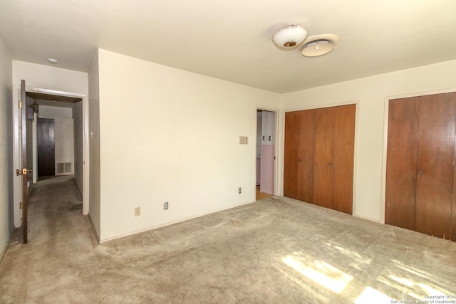 unfurnished bedroom featuring visible vents, multiple closets, and carpet floors