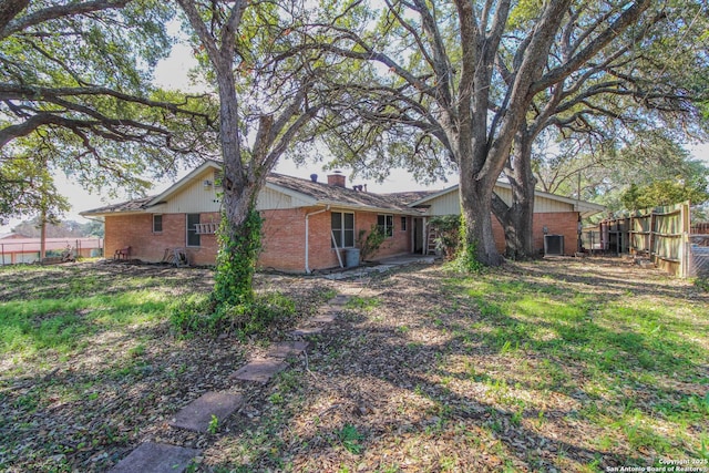 back of property with fence, brick siding, and a chimney