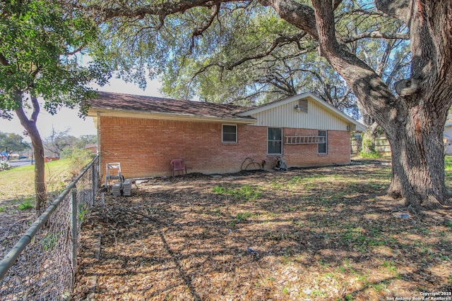 back of property featuring fence and brick siding