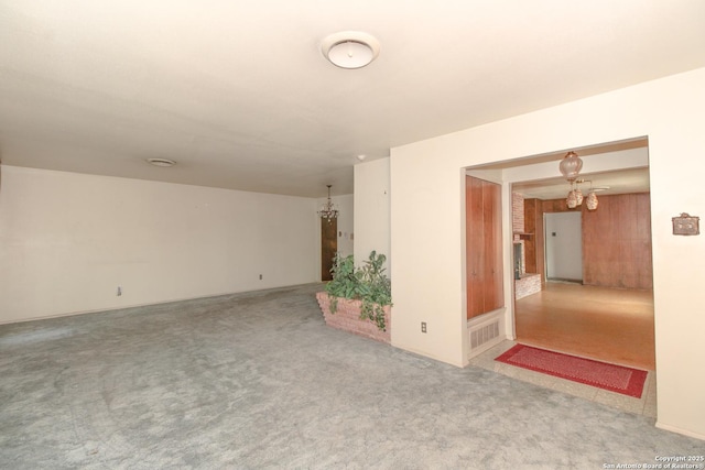 carpeted empty room featuring visible vents and a chandelier