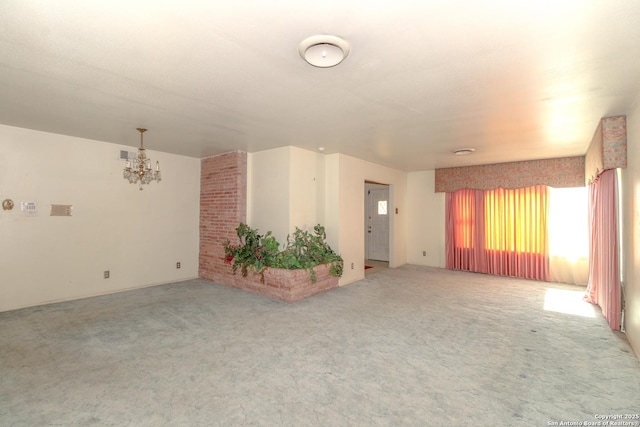 empty room featuring a notable chandelier, visible vents, and light carpet