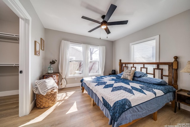 bedroom featuring light wood-style floors, baseboards, a closet, and ceiling fan