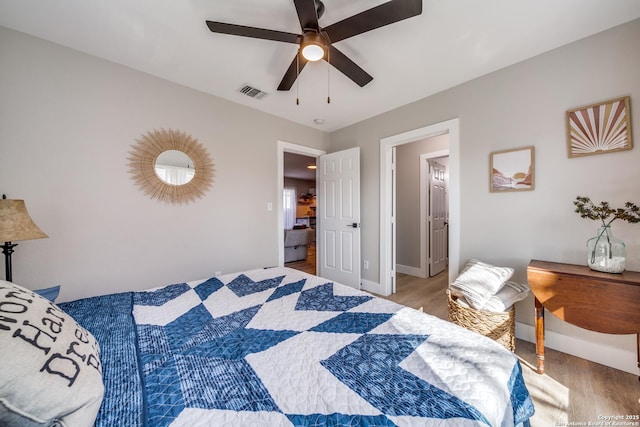 bedroom featuring visible vents, baseboards, ceiling fan, and wood finished floors