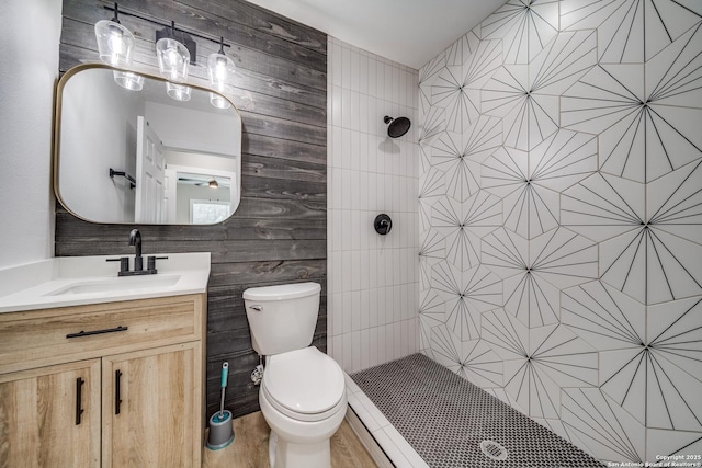 full bathroom featuring a tile shower, toilet, and vanity