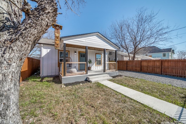 view of front facade featuring a porch, a chimney, board and batten siding, and fence