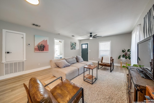 living room with visible vents, light wood-style flooring, baseboards, and a ceiling fan