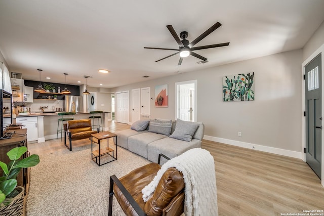 living room featuring recessed lighting, a ceiling fan, light wood-type flooring, and baseboards