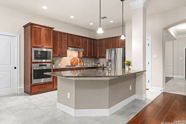 kitchen featuring visible vents, dark stone counters, arched walkways, appliances with stainless steel finishes, and under cabinet range hood