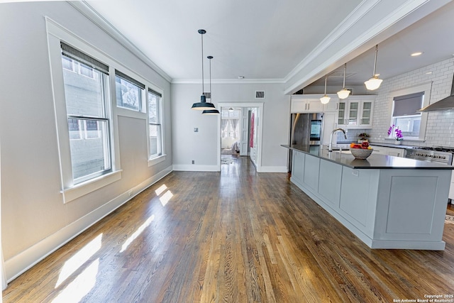 kitchen with ornamental molding, a sink, dark countertops, appliances with stainless steel finishes, and white cabinets