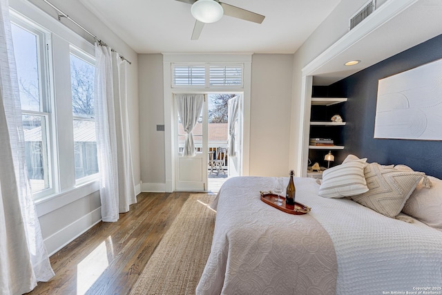 bedroom featuring multiple windows, wood finished floors, visible vents, and baseboards