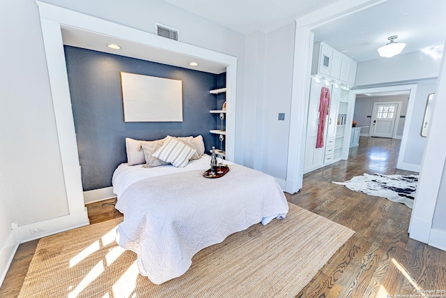 bedroom with visible vents, baseboards, and wood finished floors