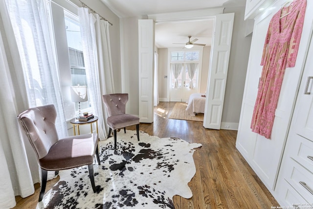 sitting room with baseboards, a ceiling fan, and wood finished floors