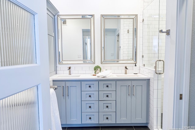 full bathroom featuring double vanity, a shower stall, and a sink