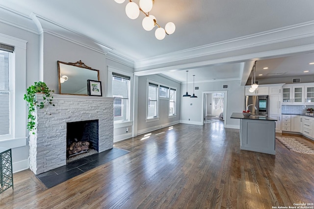 unfurnished living room with a notable chandelier, a fireplace, crown molding, baseboards, and dark wood-style flooring